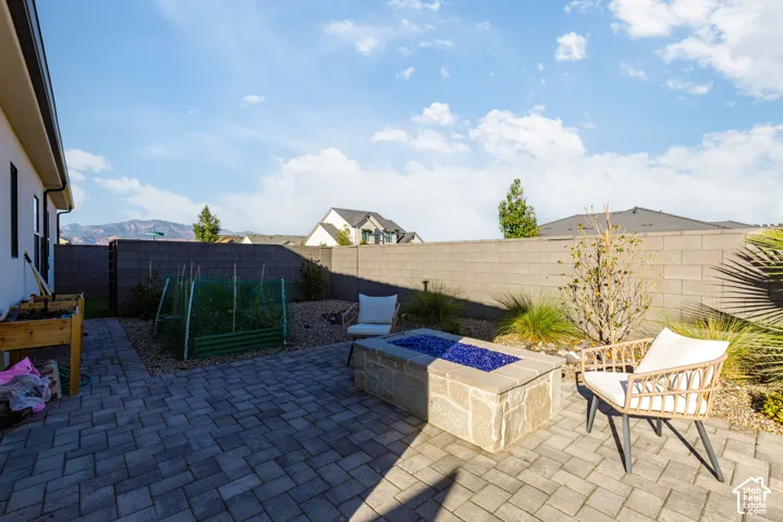 Pavered patio with a built-in stone fire pit, surrounded by low-maintenance landscaping and a block wall