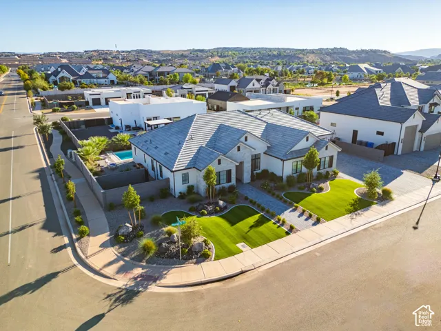 Modern home with a light-toned exterior, gabled roofline, front yard landscaping, and a private swimming pool