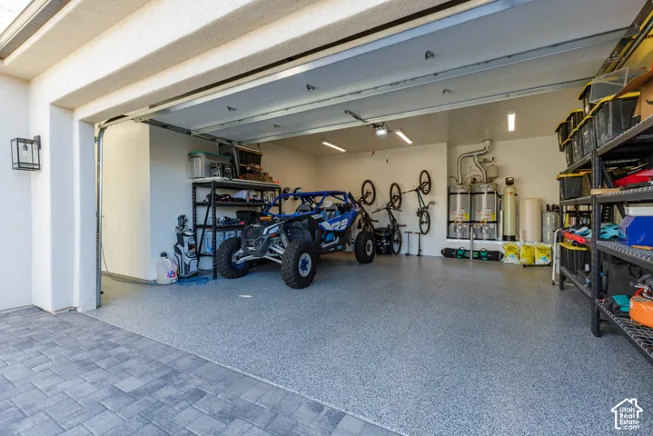 Garage space featuring a speckled epoxy floor coating, recessed lighting, and wall-mounted storage solutions