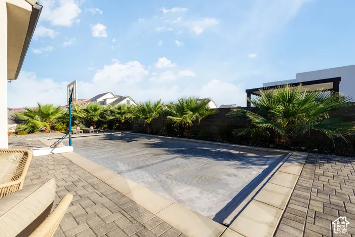 Paved patio area, covered pool, and mature palm trees