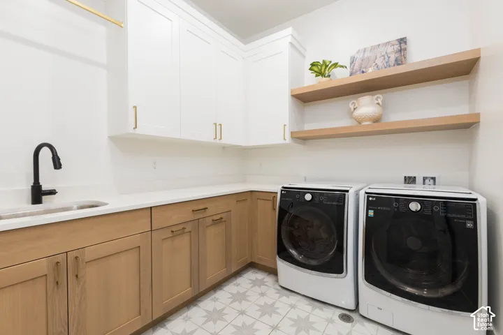 White cabinetry, wood-finish base cabinets, light-toned countertop, sink with a matte black faucet, and patterned floor tile
