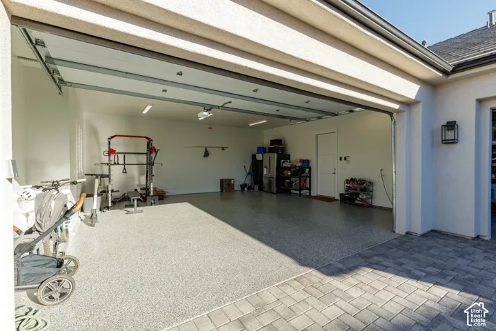 Attached two-car garage featuring an epoxy-coated floor, overhead lighting, and an access door