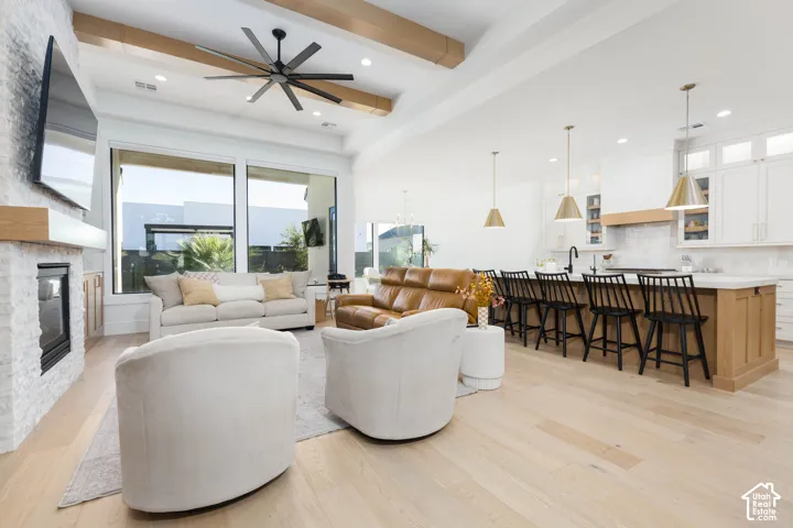 Open-concept living space with light wood-finish flooring, vaulted ceilings, and exposed wood beams