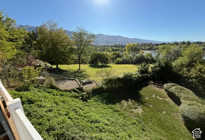 Expansive landscaped grounds with a mountain backdrop and distant body of water