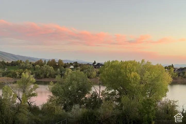 Waterfront setting with mature trees and distant mountains