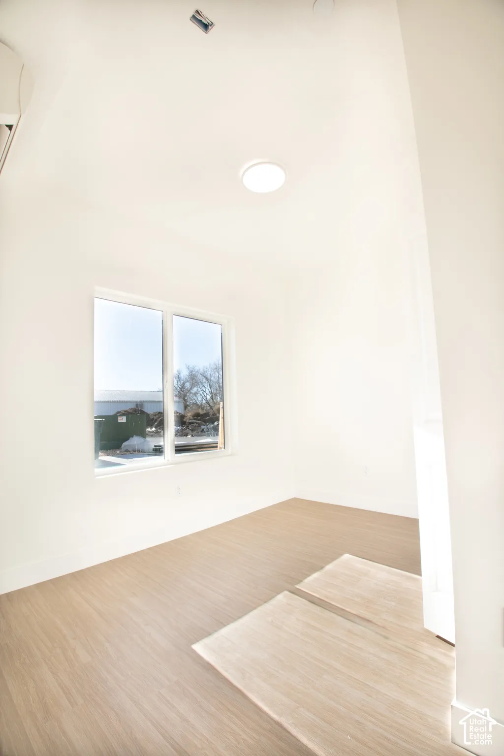 Wood-finish flooring, white walls, and a window with a simple frame