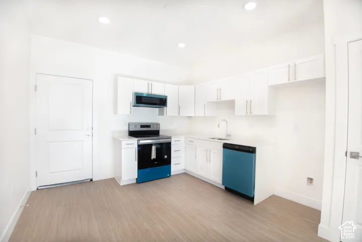 Kitchen featuring white cabinetry, light-toned wood-finish flooring, stainless steel appliances, and recessed lighting