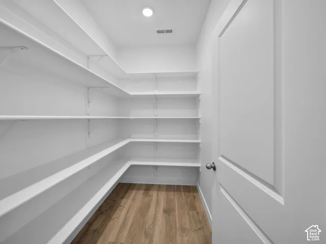 Integrated recessed lighting, extensive white shelving, wood-finish flooring, and white paneled door