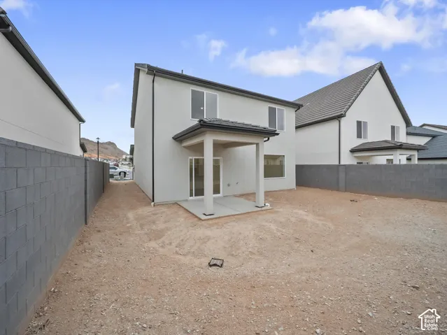 Rear exterior featuring a covered patio, sliding glass door, and perimeter block wall fencing