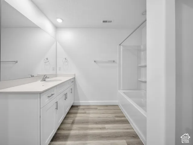 White vanity with an integrated sink, polished chrome faucet, and expansive wall-mounted mirror
