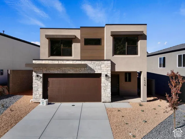 Contemporary exterior featuring stacked stone accents, stucco siding, a wood-finish garage door, and a concrete driveway