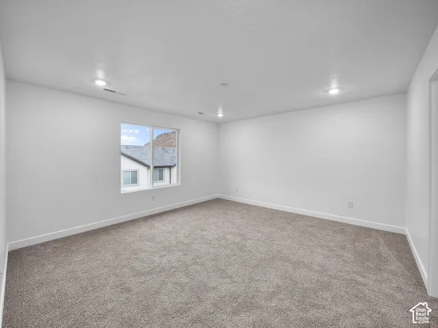Recessed lighting, neutral wall paint, carpet flooring, a large window, and white trim