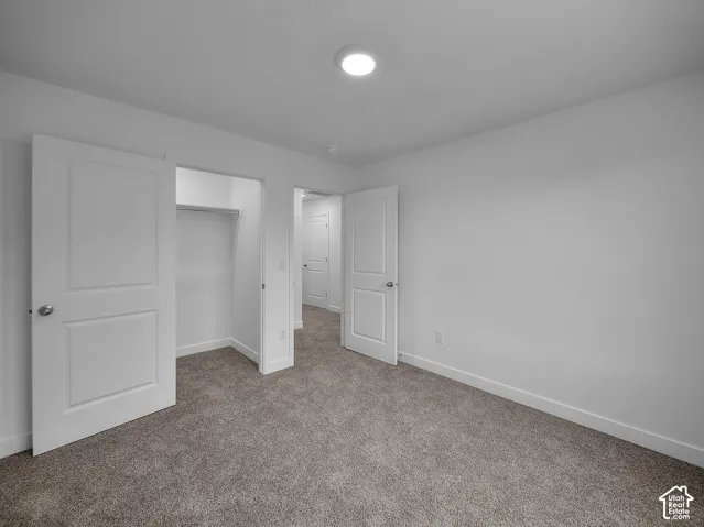 Wall-to-wall carpeting in a neutral tone, white interior doors with satin nickel hardware, recessed ceiling lighting, and a built-in closet with a hanging rod