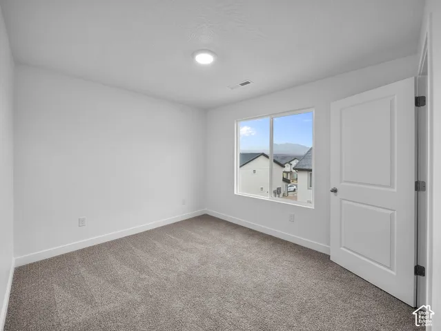 Recessed ceiling lighting, white walls, gray carpet flooring, window with natural scenery, and a paneled interior door