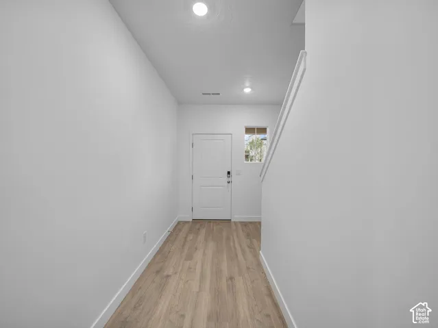 Entryway with wood-finish flooring, recessed lighting, and a paneled door