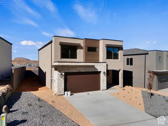 Modern exterior with stucco and stone accents, featuring a two-car garage and concrete driveway