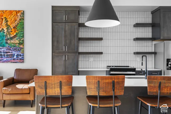 Vertical tile backsplash, matte black kitchen faucet, built-in stainless steel refrigerator, dark wood-finish cabinetry, and open shelving