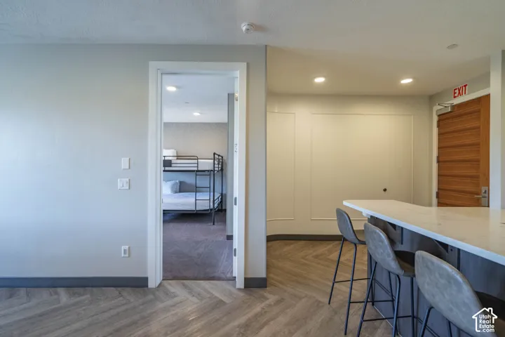 Wood-finish herringbone flooring, recessed lighting, and a white countertop island
