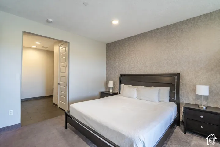 Recessed lighting, textured accent wall, wood-finish flooring, paneled door, and neutral color palette