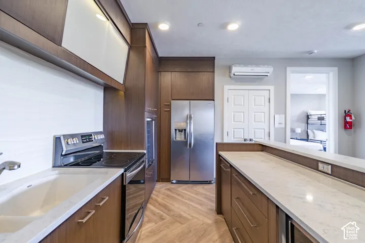 Kitchen featuring wood-finish cabinetry, stainless steel appliances, built-in oven, integrated cooktop, and stone countertops