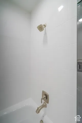 White subway tile shower surround with brushed nickel fixtures and an integrated bathtub