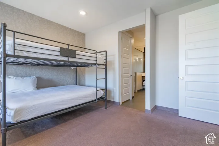 Recessed ceiling lighting, textured accent wall, paneled interior doors, and carpet flooring
