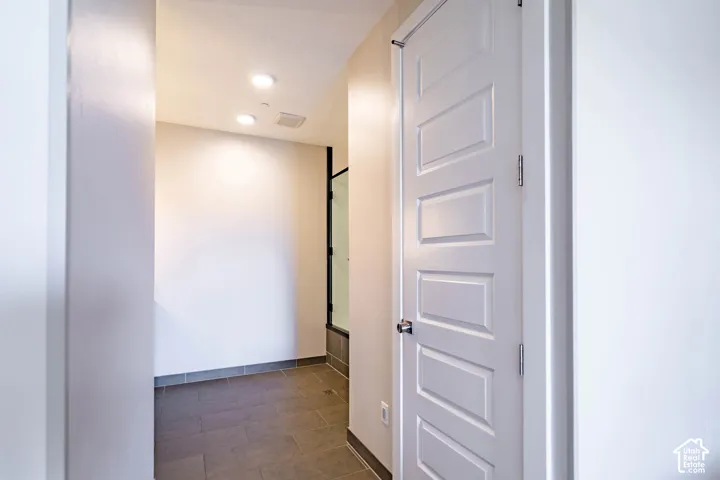 Recessed lighting illuminates the hallway with paneled interior doors and tile flooring