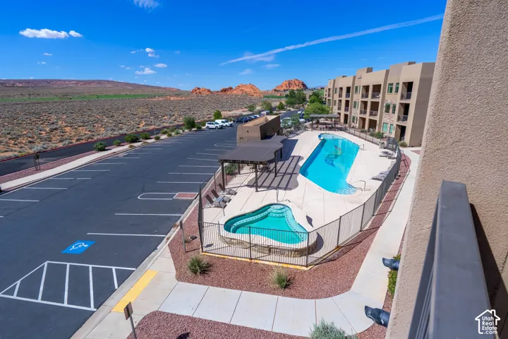 Multi-story building featuring balconies, an outdoor pool, and an adjacent spa, set against a desert landscape