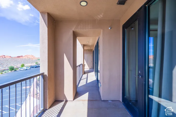 Exterior walkway with stucco finish, recessed lighting, and dark-framed glass doors