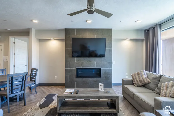 Stone-tiled fireplace with an inset linear firebox, wood-finish flooring, recessed lighting, and a ceiling fan