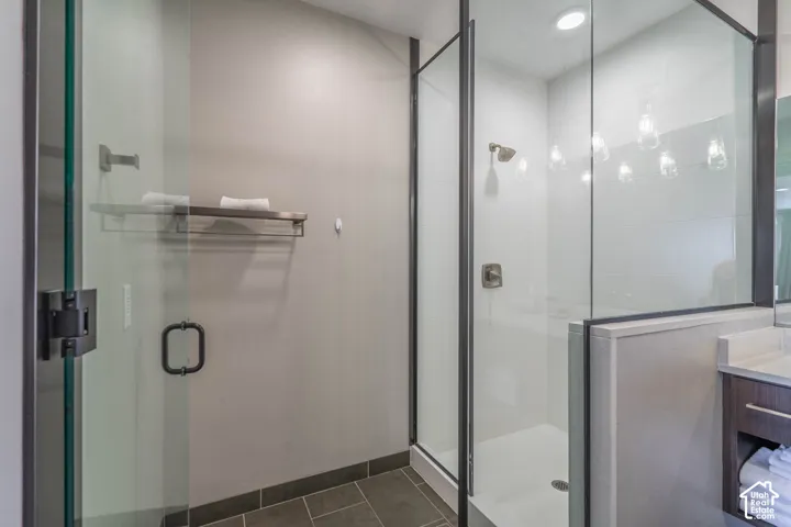 Glass-enclosed shower with a brushed nickel shower head, recessed lighting, and a white tiled shower surround