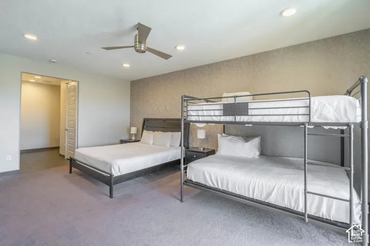 Recessed lighting, ceiling fan, textured accent wall, and built-in closet with bifold doors