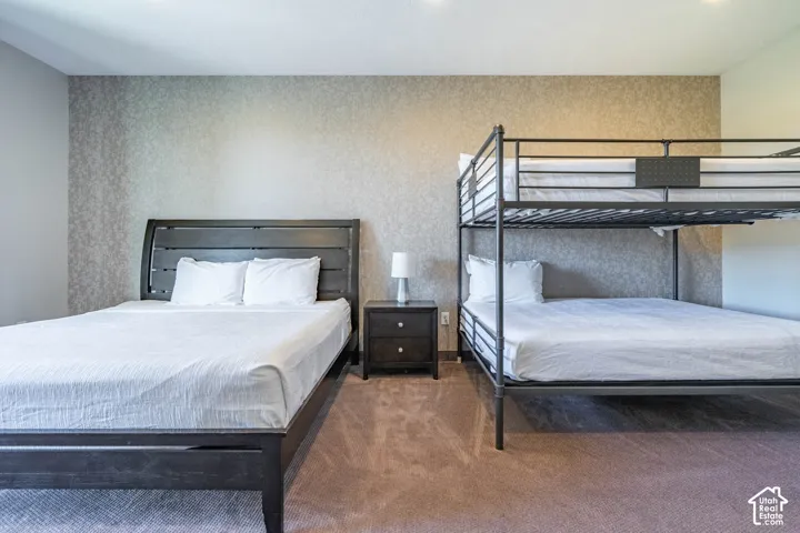 Textured wall finish, recessed ceiling lighting, wall-to-wall carpeting, and a dark wood-finish nightstand