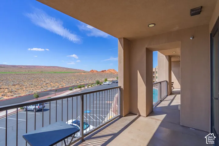 Covered balcony with desert landscape and distant red rock formations, featuring a black metal railing