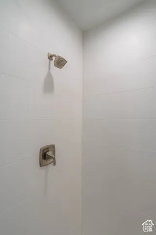 White tiled shower enclosure with a brushed metal shower head and control valve