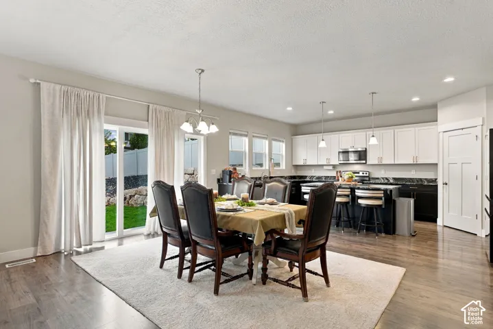 Dining area off the kitchen with white upper cabinetry, a kitchen island with seating, pendant lighting, and sliding glass door access to the exterior