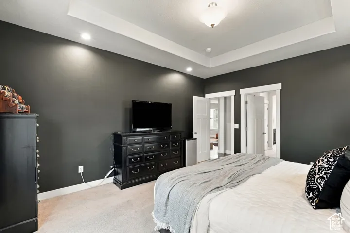 Tray ceiling with recessed lighting and a central flush-mount fixture, complemented by two panel doors with overhead transoms