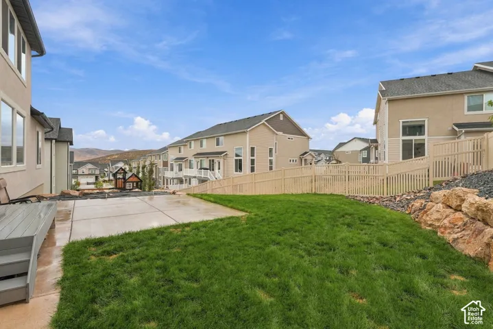 Expansive backyard featuring a concrete patio, composite decking, and a manicured lawn