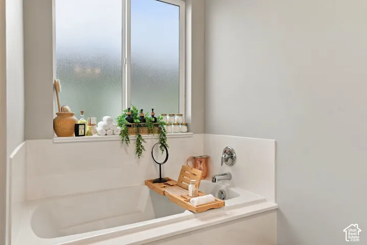 Built-in soaking tub with chrome fixtures and a surrounding white tile deck