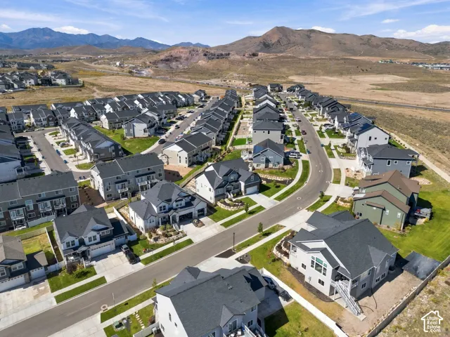 Residential development featuring a variety of single-family homes and townhomes, curved streets, sidewalks, and landscaped common areas
