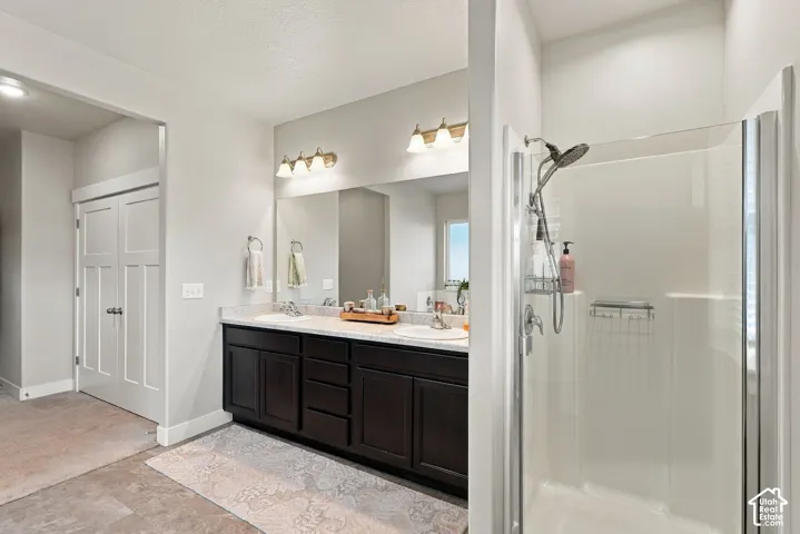 Dual vanity with dark wood-finish cabinetry, light stone-finish countertop, and undermount sinks