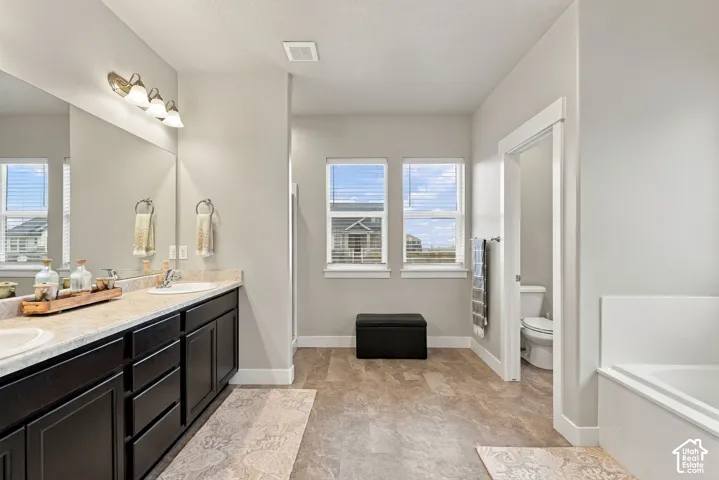 Double vanity with dual sinks and ample countertop space, complemented by a built-in bathtub and separate water closet