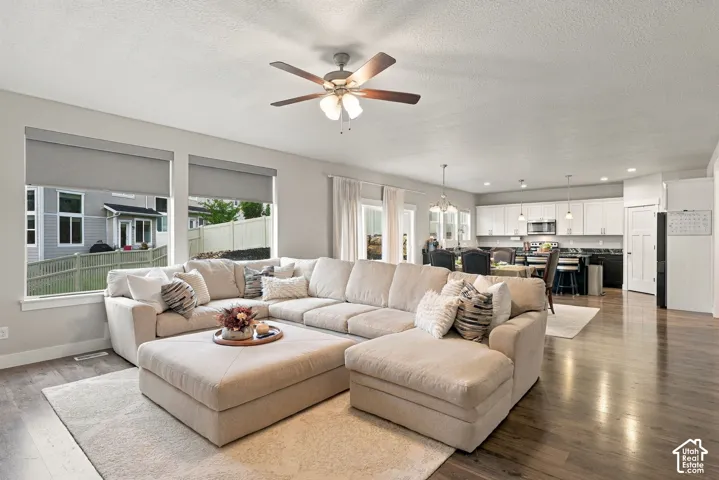 Open-concept living space featuring wood-finish flooring, recessed lighting, a ceiling fan, and multiple windows with roller shades
