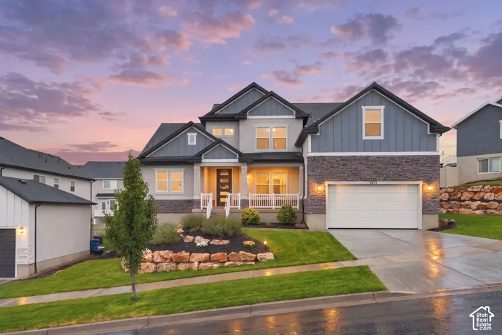 Two-story home with a multi-textured facade, attached garage, and a covered porch