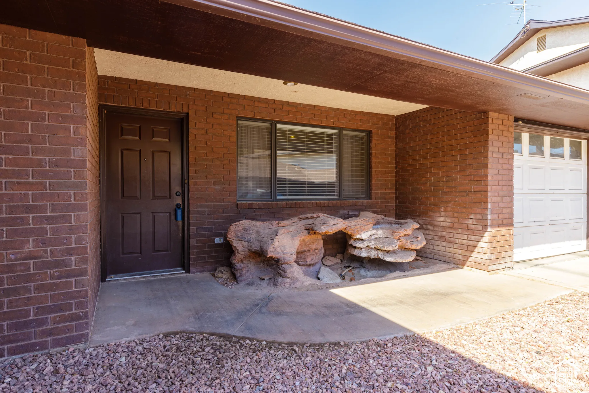 Brick exterior with covered entry, a paneled front door, and an integrated garage