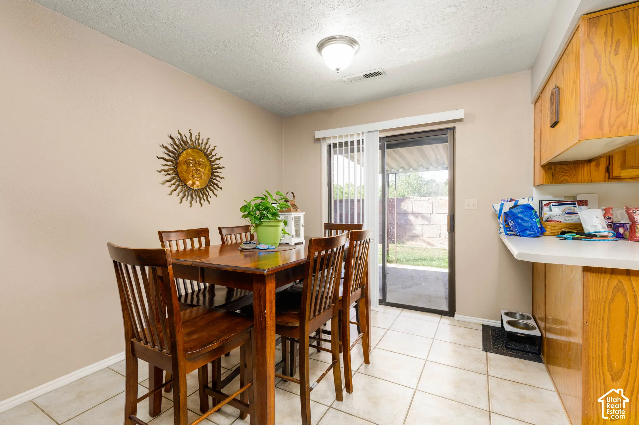Tile flooring, wood-finish cabinetry, white countertop, sliding glass door, and recessed lighting
