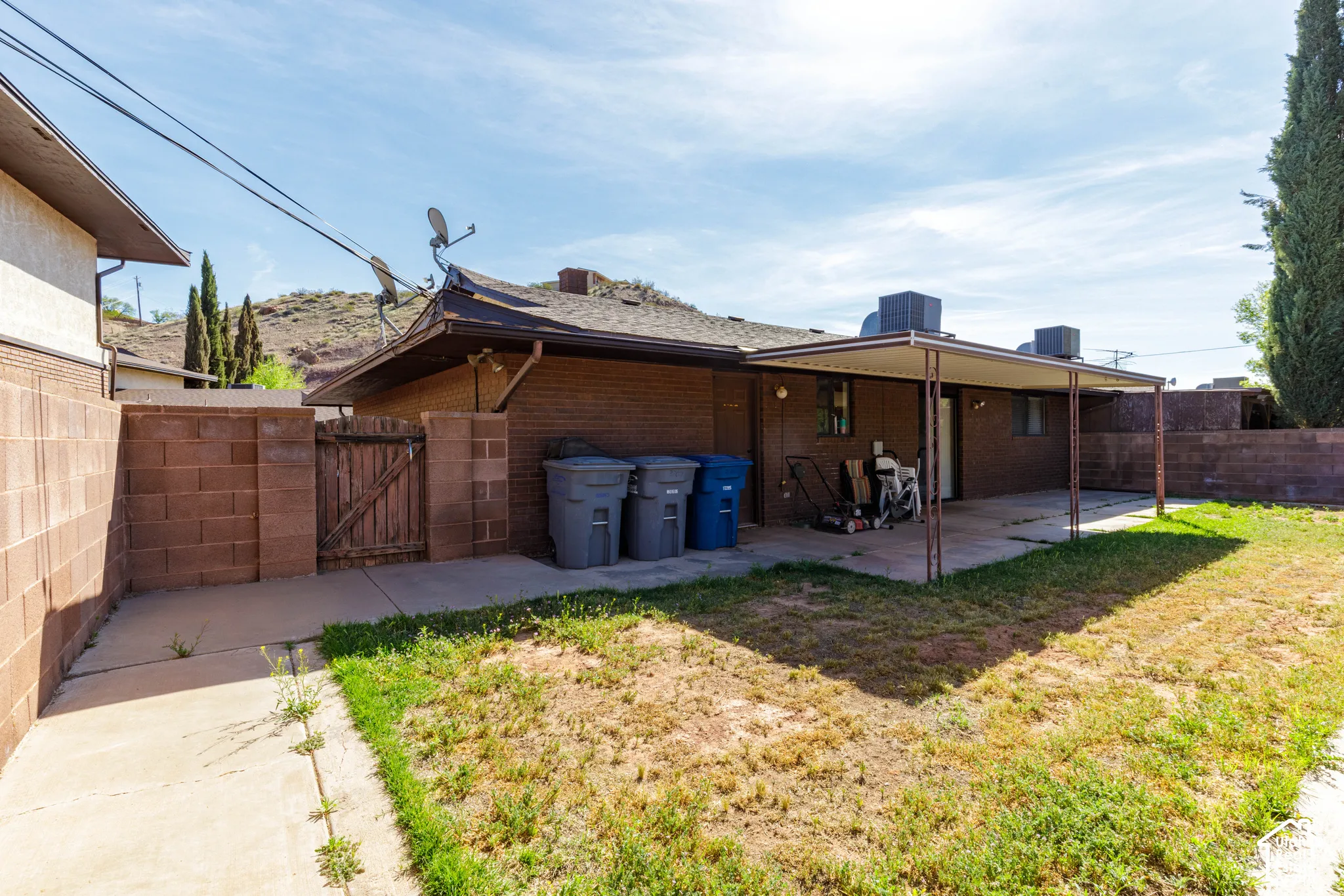 Brick exterior with a covered patio, concrete slab, and block wall fencing