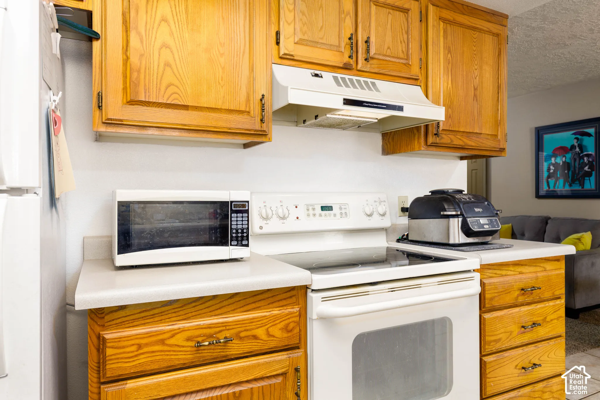 Wood-finish cabinetry and drawers, light-toned countertops, and a white range with an integrated oven