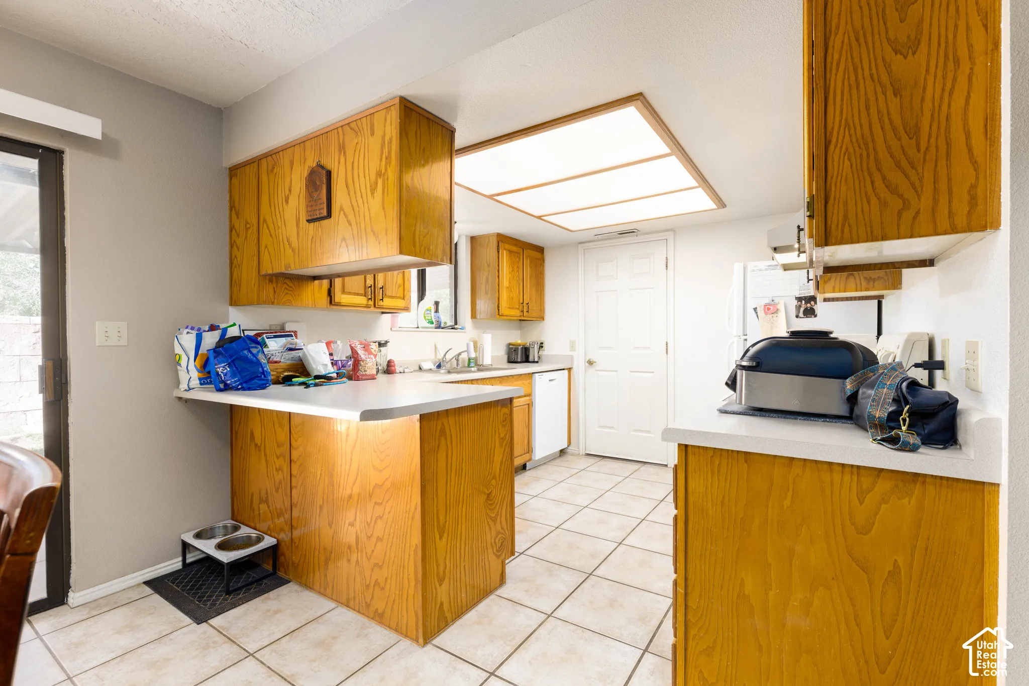 Kitchen featuring wood-finish cabinetry, light-toned countertops, and tile flooring