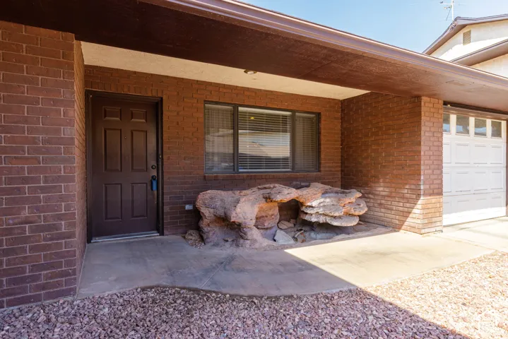 Brick exterior with covered entry, a paneled front door, and an integrated garage